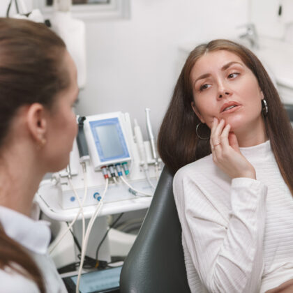 Patient experiencing dental pain and a dental emergency. Showing the dentist where her pain is.